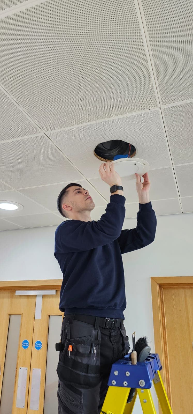 Rossair engineer installing a ceiling-mounted detector